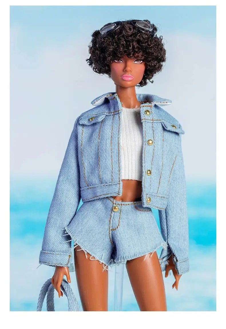 Une poupée Barbie aux cheveux foncés bouclés, portant des lunettes de soleil posées sur la tête, vêtue d’une veste en jean à lavage clair et de shorts assortis, présentée dans un ensemble de vêtements et d’accessoires de mode pour poupée à l’échelle 1/6.