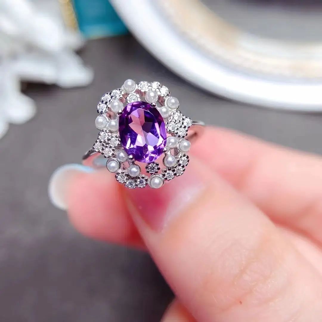 Une bague en argent étincelante de l’ensemble de bijoux en argent sterling avec quartz rose, présentant au centre une améthyste taillée en ovale entourée de perles délicates et de petits diamants.