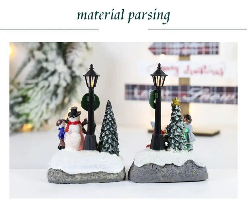 2つのクリスマスハウスライトの場面を用いた、LED雪だるまフィギュリンのディスプレイ。雪だるま、子ども、木々が、岩状の台座上に配置されています。