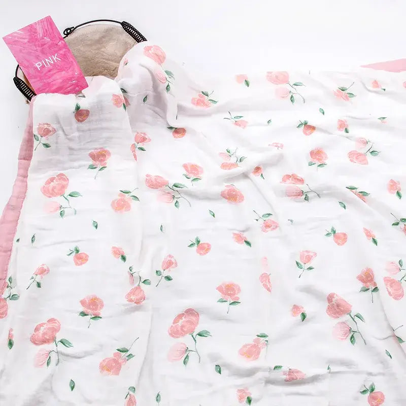 Eine weiche, weiße Bambus-Baumwoll-Decke für Babys (Swaddle) mit floraler Struktur, mit einem zarten Muster aus rosa Rosen und grünen Stielen.