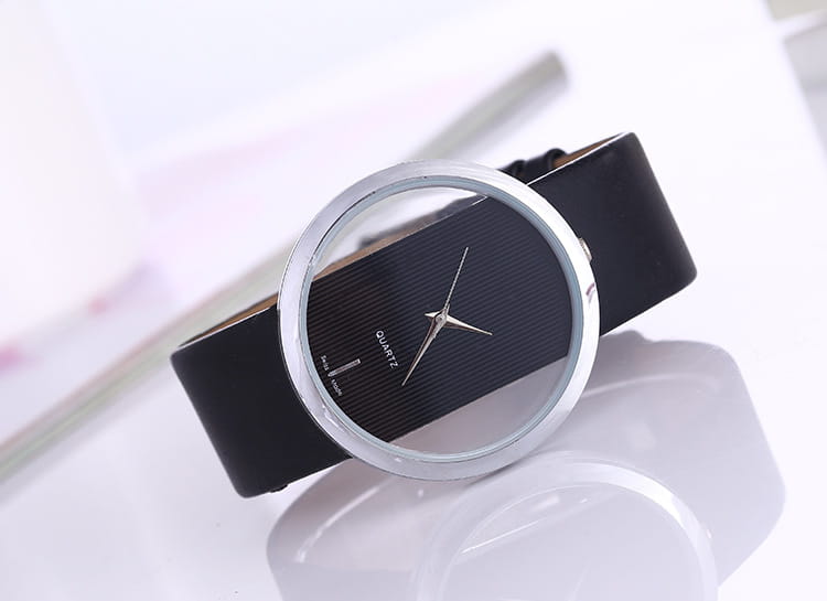 A women luxury leather quartz watch with a sleek black leather strap and minimalist silver-toned case and dial featuring subtle horizontal texturing on the transparent face.