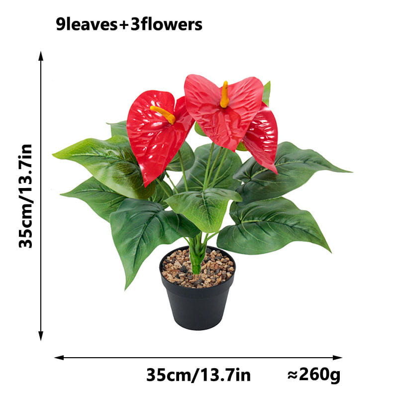 Artificial red anthurium potted plant with vibrant red flowers and glossy green leaves in a black plastic container filled with decorative pebbles.