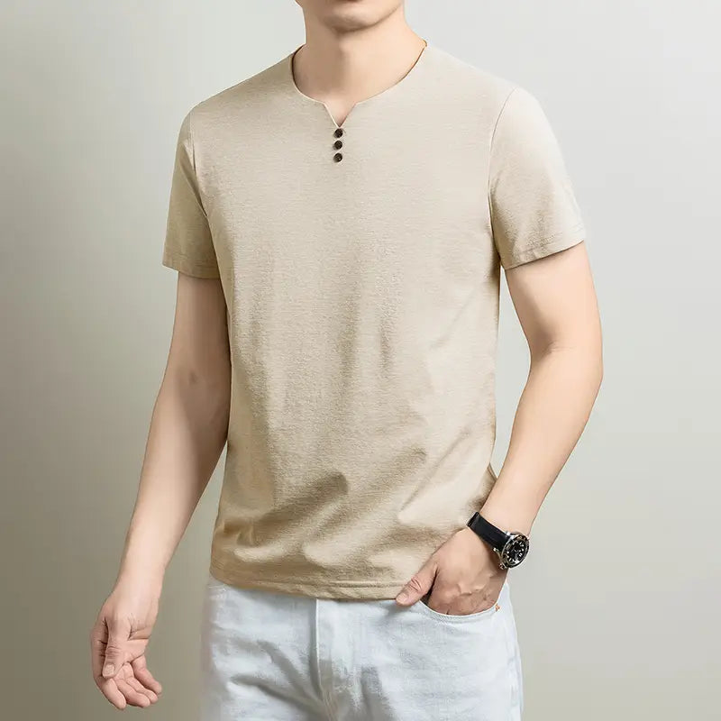 Camisa henley de manga corta color beige, con tres botones negros en el cuello, hecha de tejido con textura para uso casual.