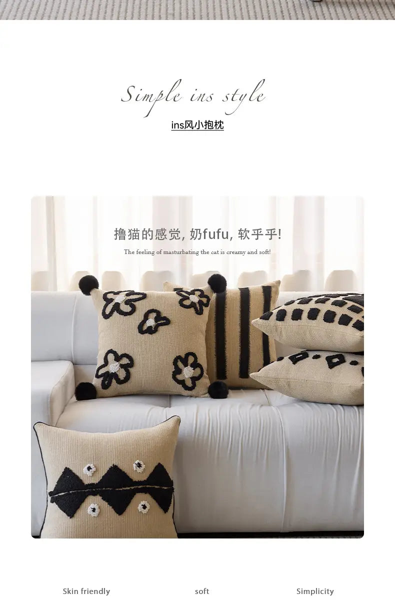 Housse de coussin bohème beige en maille, avec des motifs floraux et géométriques brodés en noir et des pompons moelleux, pour la décoration du salon.