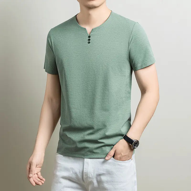 Una camisa tipo henley de manga corta para hombre en verde salvia suave, con tres botones oscuros en el cuello y un ajuste relajado informal con textura.