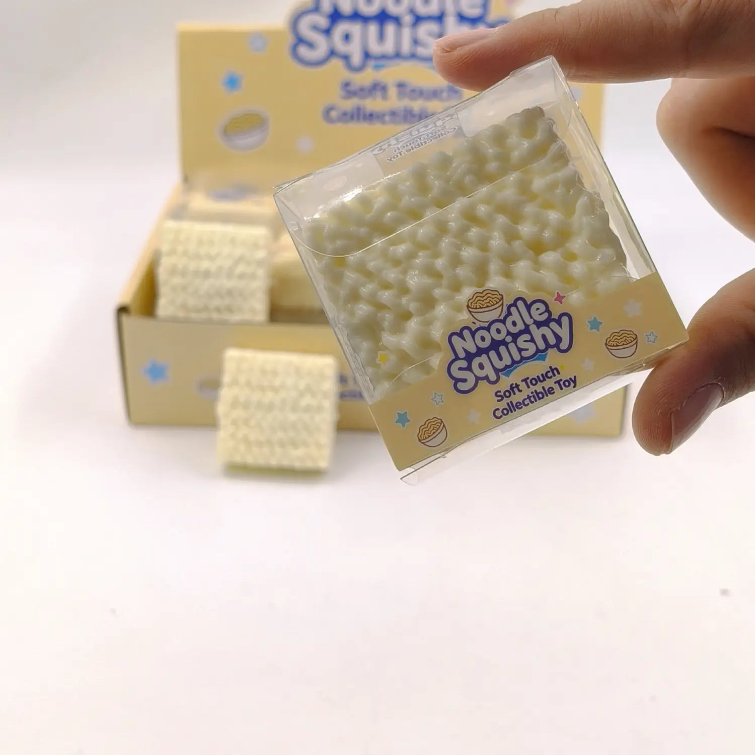 A creamy white textured noodle-shaped squishy toy made of soft material in a clear plastic package labeled noodle squishy designed for stress relief and building block play.