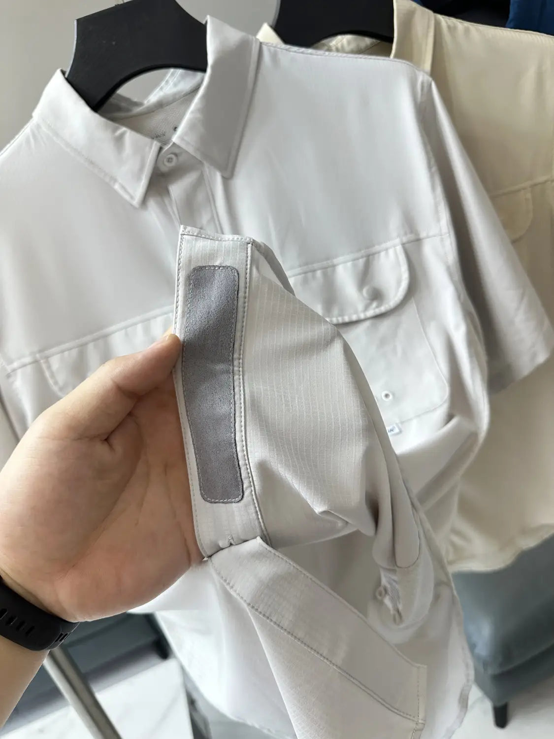 Ein markant weißes Herren-Stretch-Outdoorhemd mit kurzen Ärmeln, subtil strukturiertem Stoff, zwei Brusttaschen und schnelltrocknendem Material.
