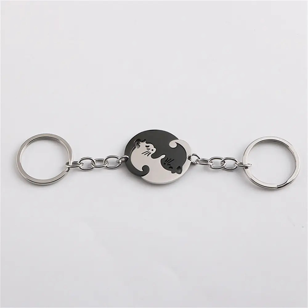 Silver-toned interlocking cat couple keychain set featuring a circular medallion with black and white yin-yang cat design connected by a chain to two metal rings.
