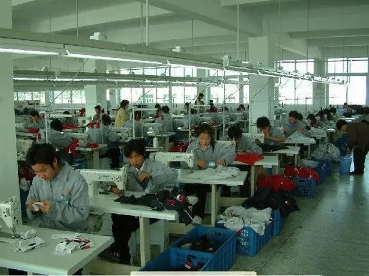gray industrial sewing machines with white accents and metal frames arranged in rows on a factory floor producing women double-breasted trench coat casual windbreakers
