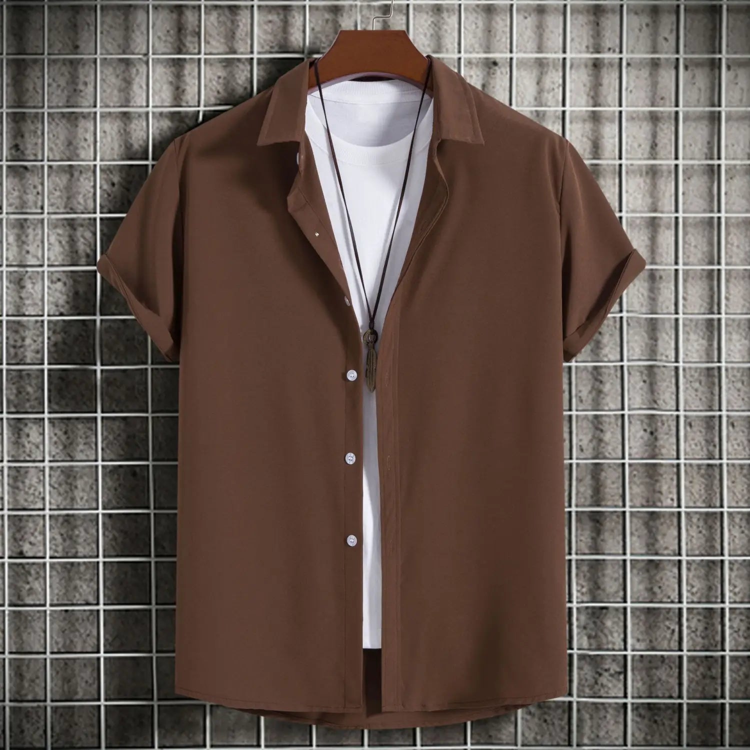chemise marron à manches courtes avec col et boutons, portée par-dessus un t-shirt blanc, suspendue sur un cintre en bois, idéale pour les chemises de plage unies de style mode pour hommes et pour le quotidien