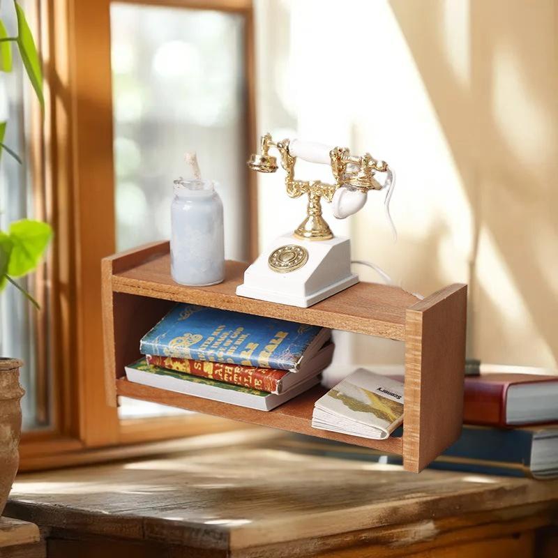 Ein vintage-stilvolles weiß-goldenes Drehtelefon mit poliertem Messingfinish, das auf einem Miniatur-Holzregal für Puppenhaus-Aufbewahrungsmöbel ruht.