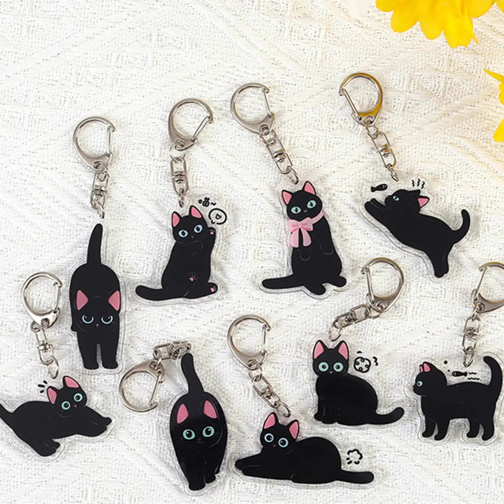 Clear acrylic black cat keychains with pink inner ears and expressive eyes attached to silver-toned metal clasps for use as cartoon animal bag charms.