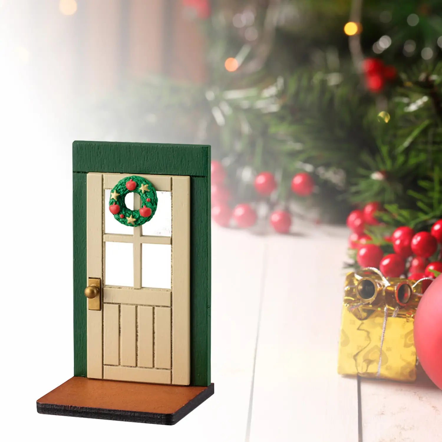 Ornement mural de porte de Noël miniature présentant une porte en bois avec une couronne verte et une poignée dorée.