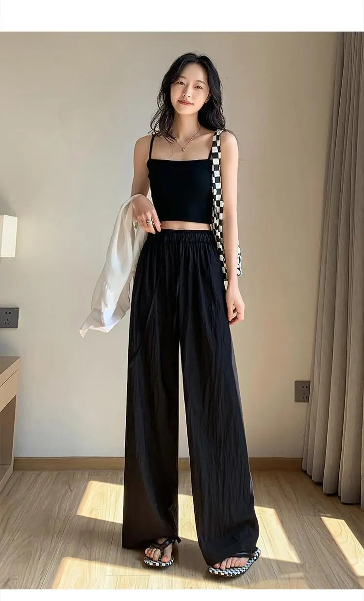 Schwarze weite Plissee-Hose für Damen mit elastischem Bund und dezentem Muster bzw. Textur, ausgelegt für die Sommerzeit.