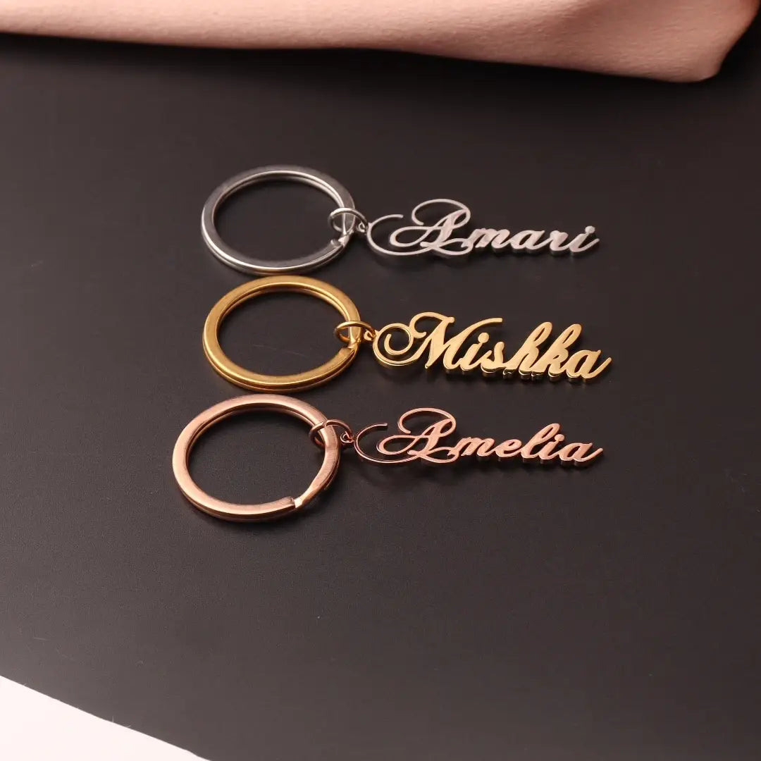three personalized stainless steel custom name keychains in silver gold and rose gold finishes featuring the names amari mishka and amelia in elegant cursive script as a gift option