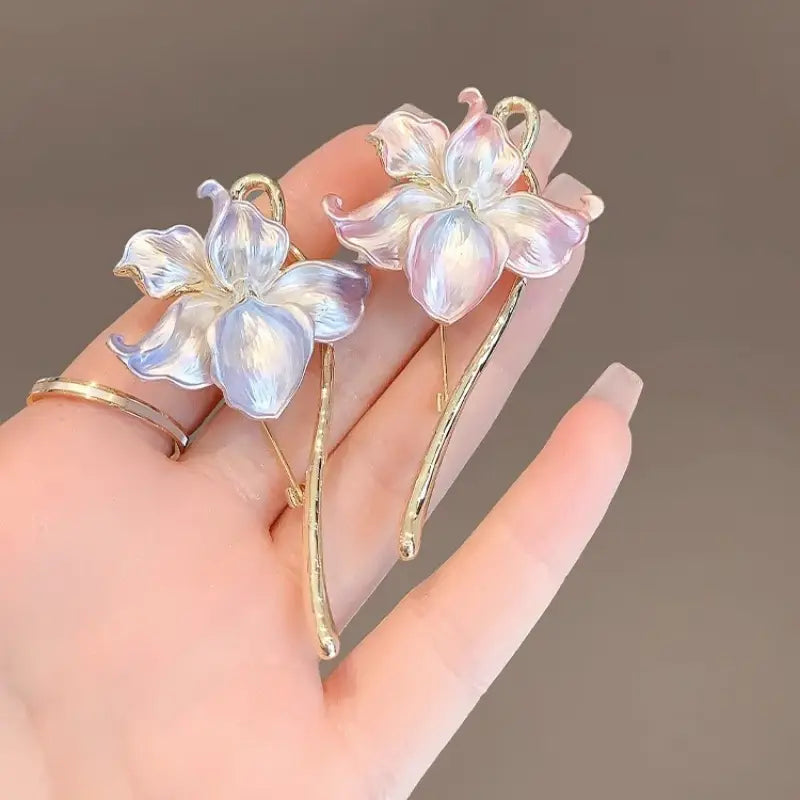 Broche-épingle émaillée en forme de fleur de lotus, présentant un délicat motif irisé en forme de fleur, avec des tiges à ton doré et des pétales translucides scintillant dans des tons pastel doux.