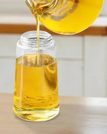un vaporisateur d’huile en verre transparent de 500 ml, bouteille doseuse de cuisine 2-en-1 remplie d’une huile de cuisine jaune doré, versée à partir d’une carafe en verre assortie