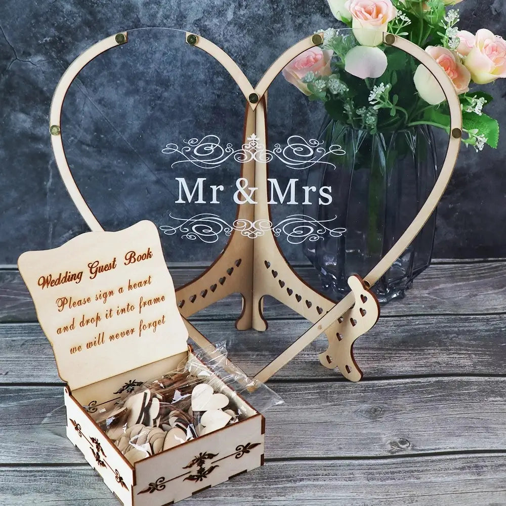 Boîte de dépôt pour livre d’or de mariage en bois en forme de cœur, comprenant un support en bois en forme de cœur avec des mentions « Mr » et « Mrs » gravées au laser et des découpes décoratives, accompagnée d’une boîte assortie de jetons blancs en forme de cœur.