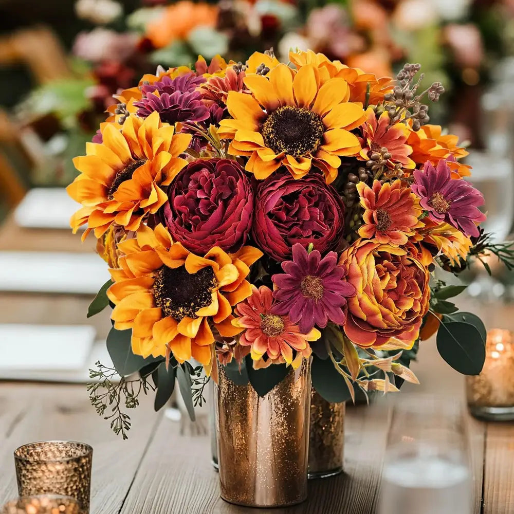 A vibrant artificial flowers autumn sunflower bouquet featuring bold yellow sunflowers and deep burgundy peonies with purple daisies in a shimmering gold metallic vase for home decoration or to send flowers.