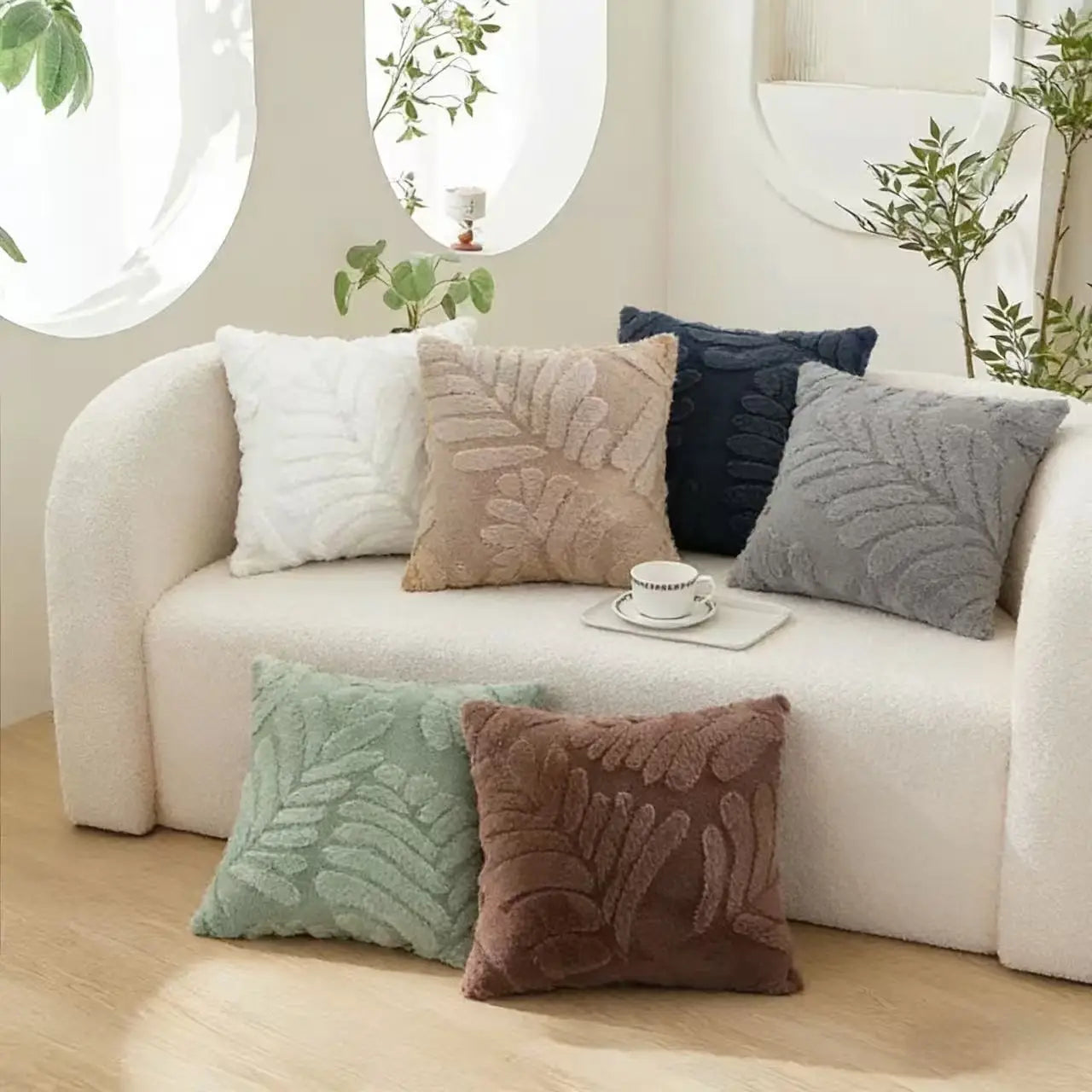 set of six plush leaf embroidered throw pillow covers in neutral tones with raised leaf embroidery arranged on a white sofa