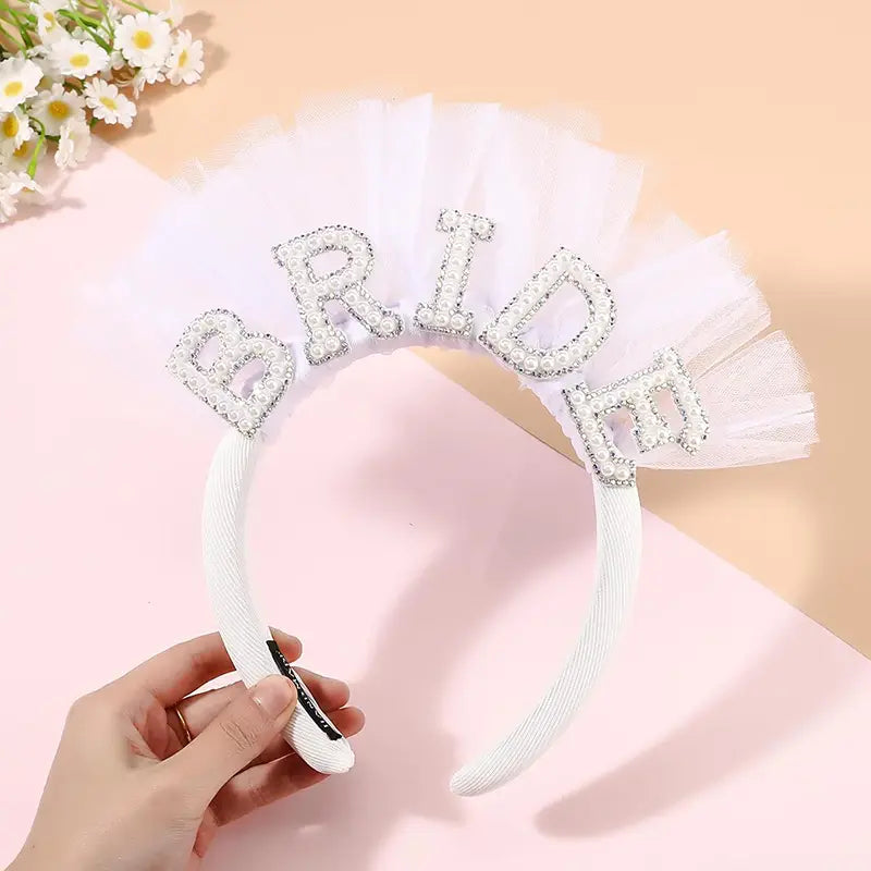 きらめくラインストーンで「Bride（花嫁）」と綴られ、繊細なチュール製ベールをあしらった、花嫁になる方パーティーセットのホワイトブライダル用ヘッドバンド。
