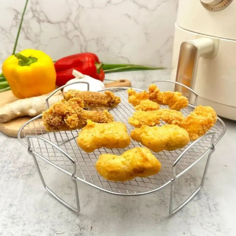 Silberner Draht-Maschen-Luftfritteusen-Grillrost aus Edelstahl, stapelbarer Korb, mit gebogenen Griffen, der goldbraune Stücke von gebratenem Hähnchen und Nuggets enthält