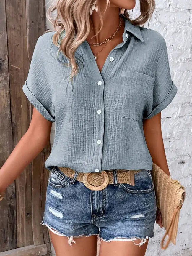 Women cotton short sleeve button up shirt in light blue with subtle textured fabric and rolled cuffs.