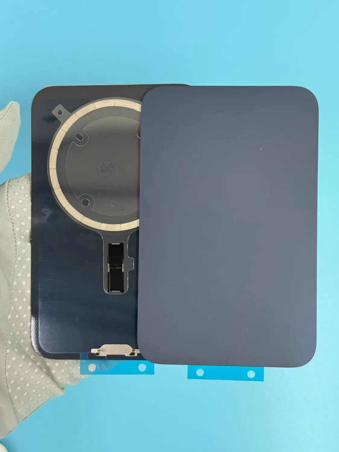 Dark gray rectangular battery cover replacement glass for iPhone 17 Pro Max with circular camera module and metallic connector shown from the back side.