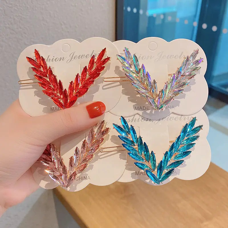 Crystal v shape hair clip set featuring red, iridescent, and blue crystal-encrusted clips with gold-tone metal bases.