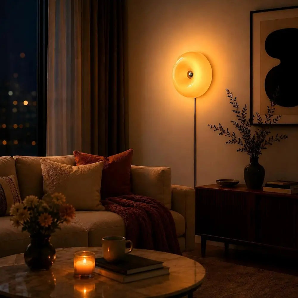 Lampe murale circulaire chaleureuse, avec un abat-jour en acrylique translucide jaune doré et un fin support noir, offrant une luminosité réglable et une commande tactile.