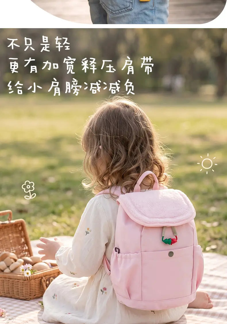 Rosa leichter Fuzzy-Rucksack für Kinder mit einer Erdbeer-Applikation auf der vorderen Tasche, entworfen für die Verwendung als Kindergartentagesrucksack.