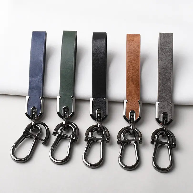 Five custom engraved leather keychains in navy olive green black tan and gray with metallic carabiner clips for personalized car key rings.
