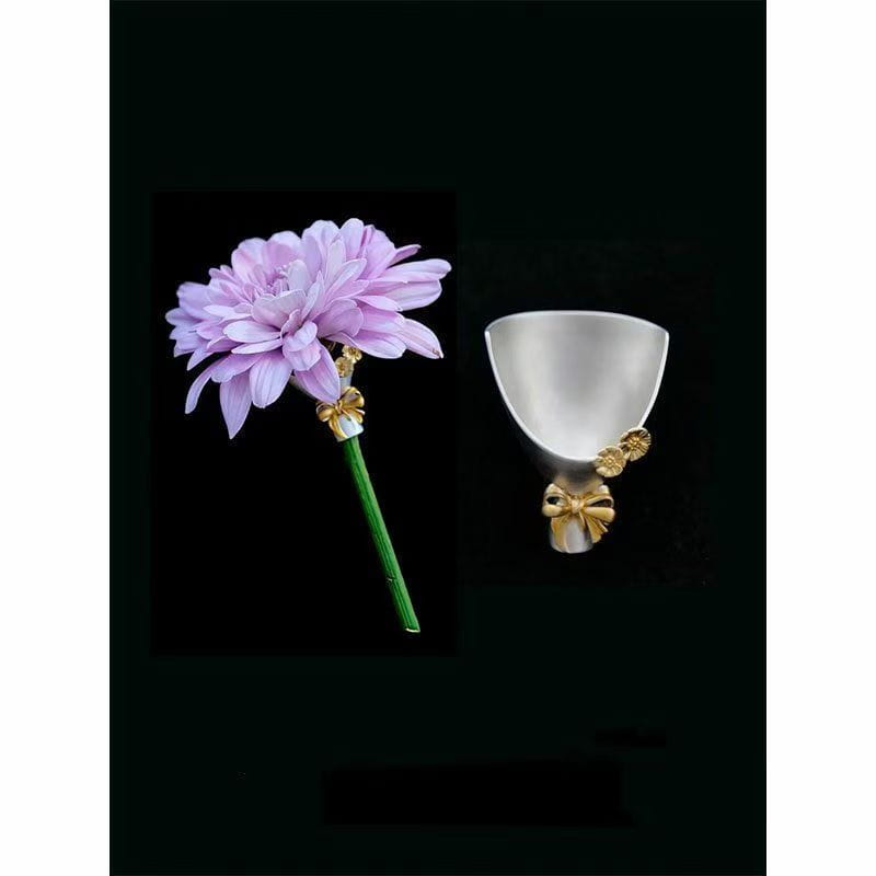 Eine zarte Lavendel-Dahlienblüten-Broschennadel mit einem grünen Stiel, der mit einer goldfarbenen Schleife und floralen Akzenten verziert ist, gestaltet als kreatives Corsage-Zubehör.