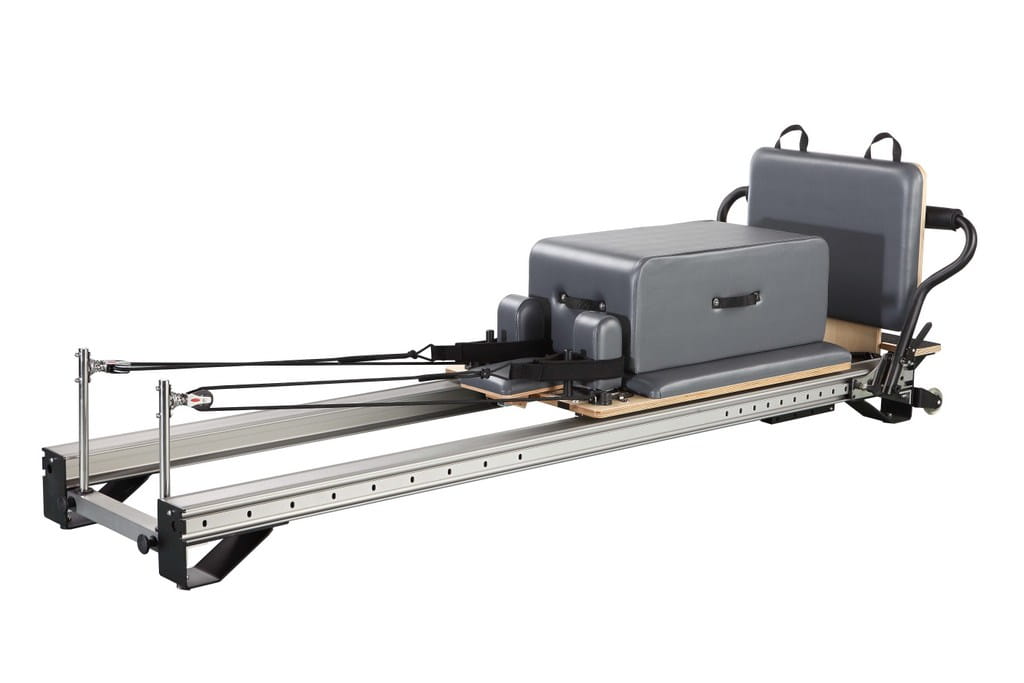 Gray upholstered Pilates reformer with metal frame and adjustable resistance bands featured in a 3-station multi-function home gym equipment.