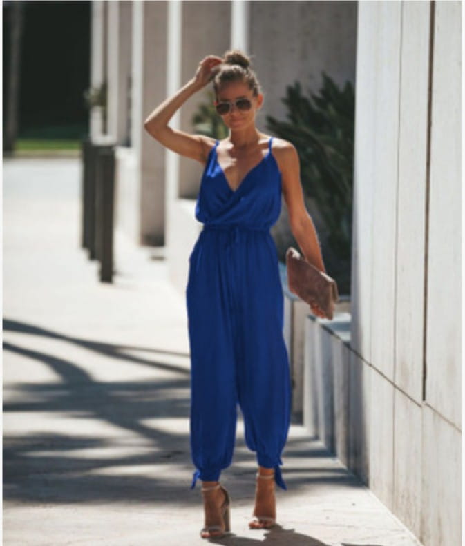 Ein lebhaftes königsblaues, ärmelloses Sommeroverall mit drapiertem V-Ausschnitt, Tunnelzug in der Taille und locker geschnittenen Haremhosen mit gebundenen Bündchen; floral im Boho-Sommerstil.