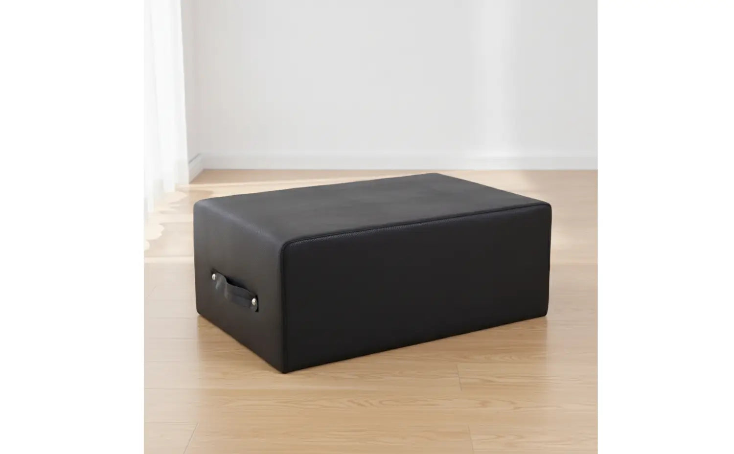 Schwarze rechteckige, gepolsterte Fitnessbox mit weicher Polsteroberfläche und robustem Griff für die Nutzung bei Pilates und im Home-Gym.