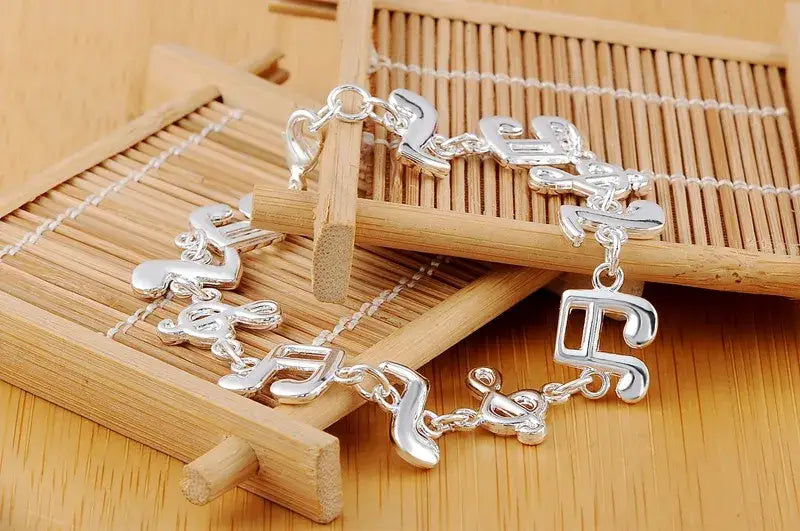 Silver musical note sterling silver bracelet with a polished reflective finish and interlocking chain links.