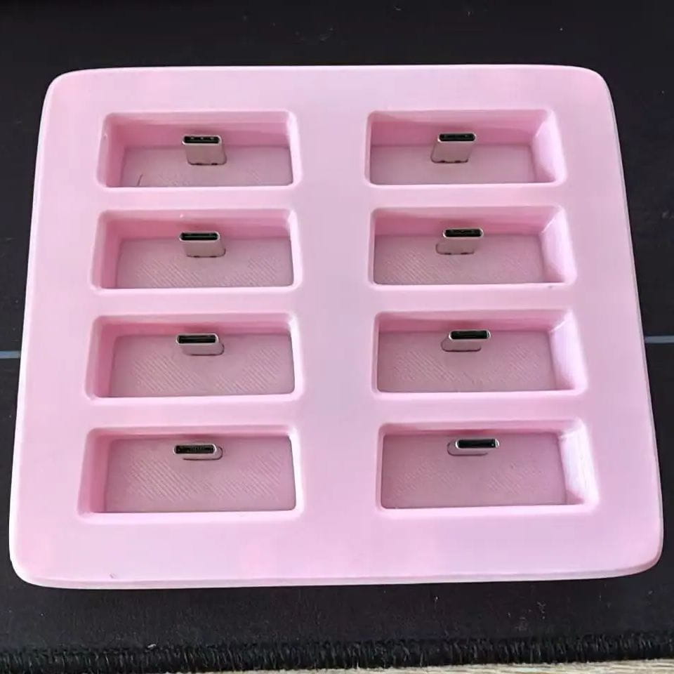 rosa Silikon-USB‑C-Lade-Dock-Schale mit acht rechteckigen Fächern, in denen jeweils ein metallischer USB‑C‑Stecker für die SlimeVR-Station untergebracht ist