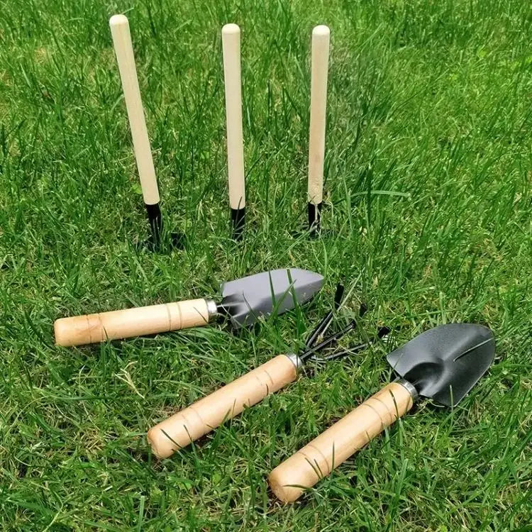 set of three small gardening tools with wooden handles and black metal heads including a garden shovel and a trowel for precise planting and digging tasks.