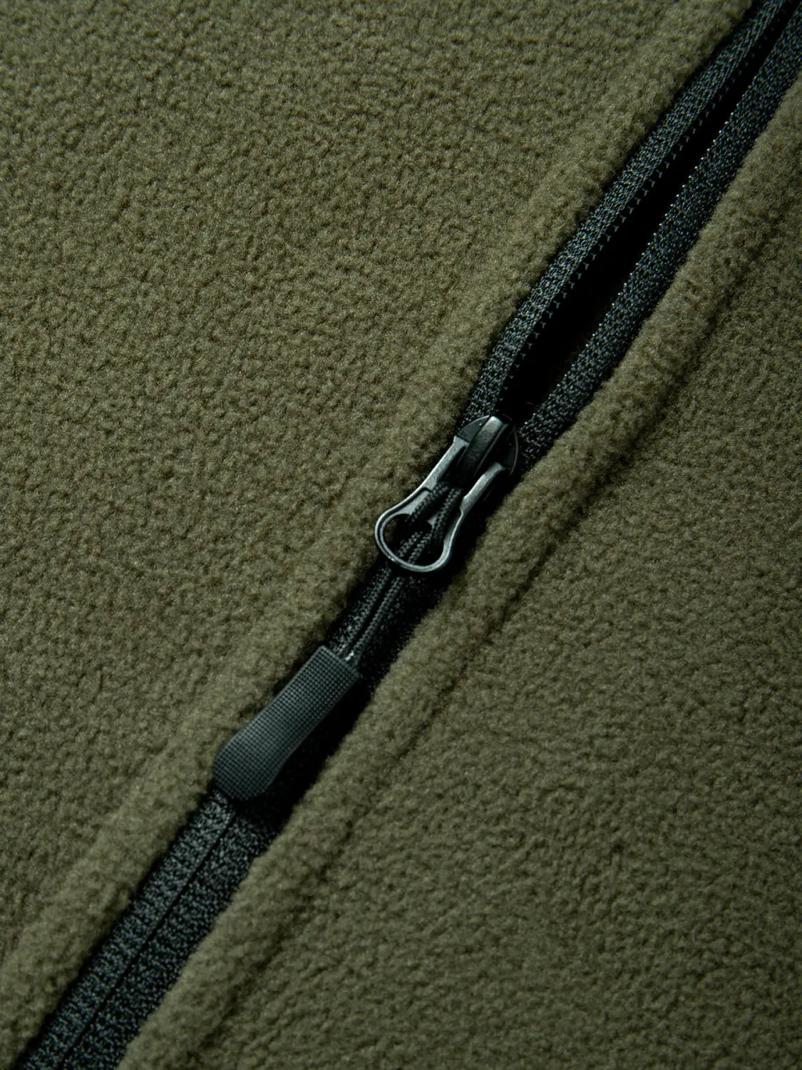 Chaqueta polar táctica verde oliva para hombre, con cremallera completa en negro y lengüeta de tirador, confeccionada con material polar cálido.