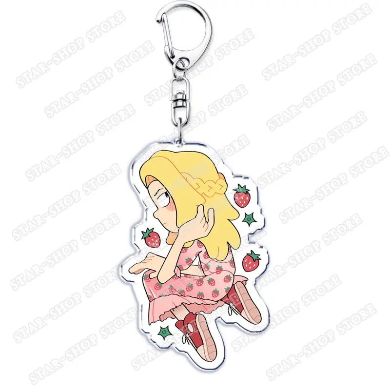 Clear acrylic Amphibia anime keychain featuring a cartoon girl with blonde hair in a pink strawberry-patterned dress and red shoes surrounded by small strawberries.
