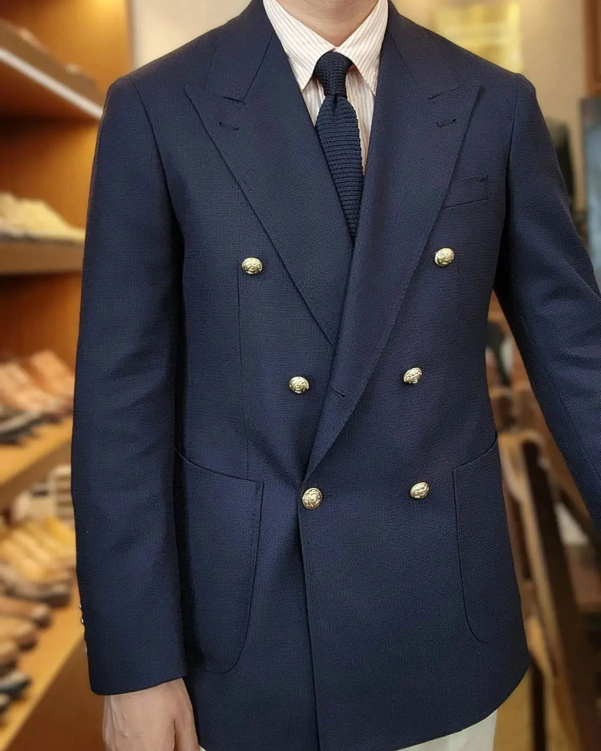 Veste de smoking bleu marine à double boutonnage avec boutons ton or, dotée d’un type de fermeture à double boutonnage adaptée à la tenue du marié.