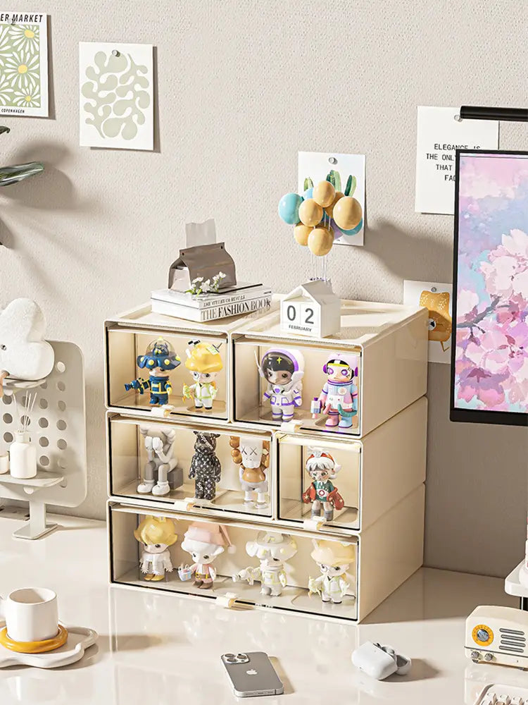 Beige translucent desktop organizer and collectible display case with clear front panels and white handles showcasing colorful collectible figurines.