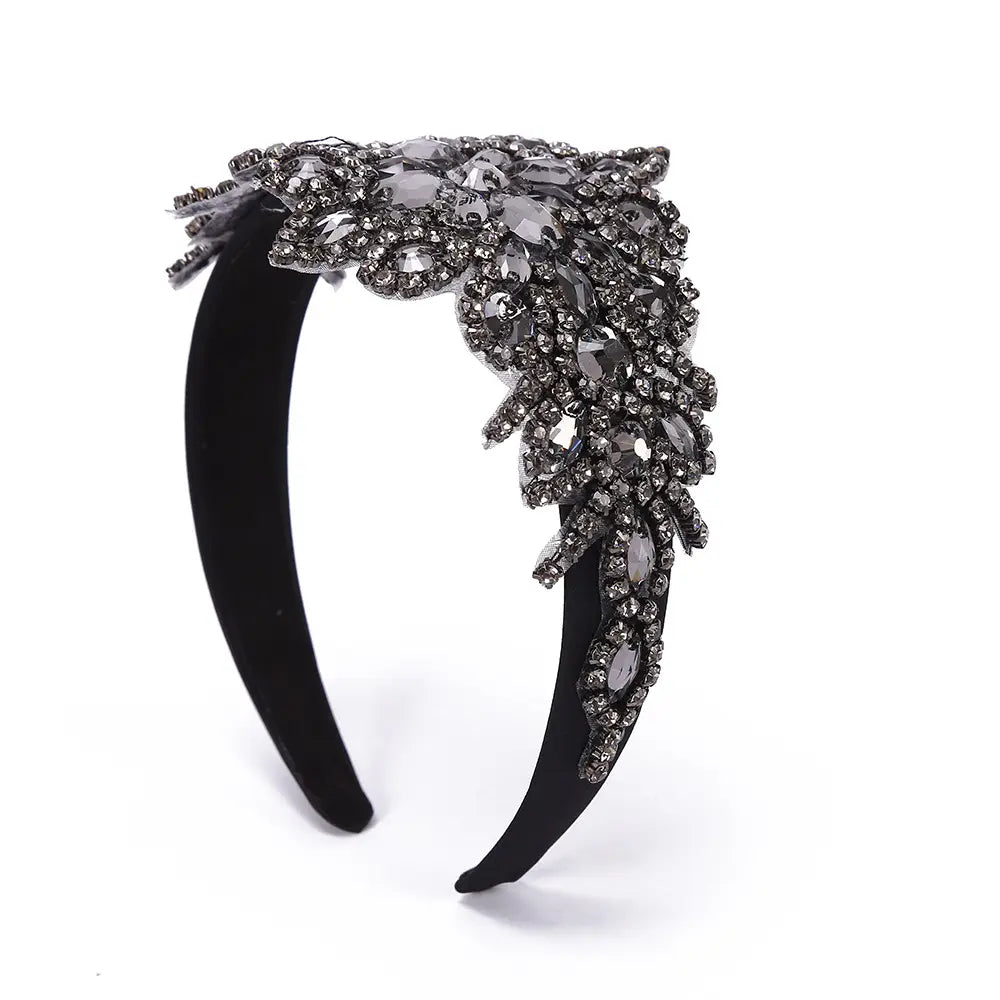 Serre-tête en fleurs de strass sur velours noir élégant, présentant une cascade complexe de cristaux gris foncé et transparents dans un dessin évoquant des plumes feuillues, pour un usage d’accessoire de coiffure en cristal.