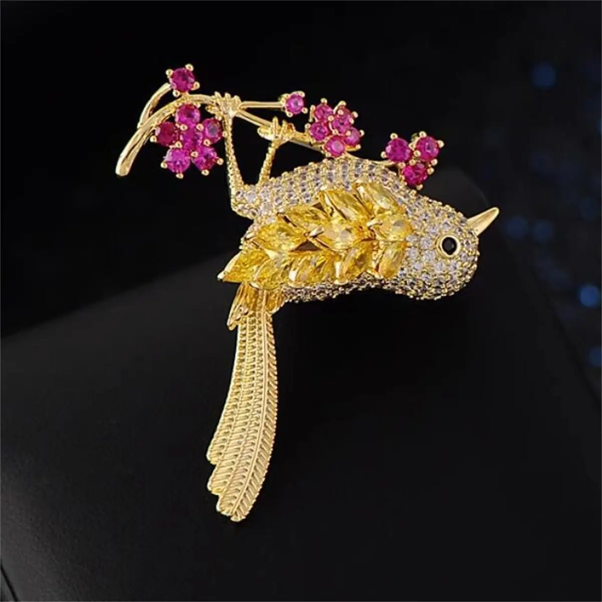 動物の衣類用ピン用アクセサリーとして、ピンクのルビージェムの花の枝とともに、黄色およびクリアのジェムストーンをあしらったゴールデンバードのブローチ。