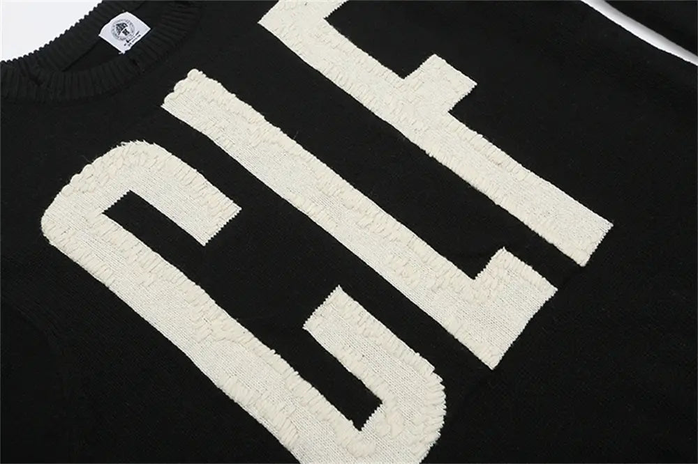 ブラックのニット素材に、太めのクリーム色の刺繍レタリングを施したブラックのオーバーサイズニットセーター。