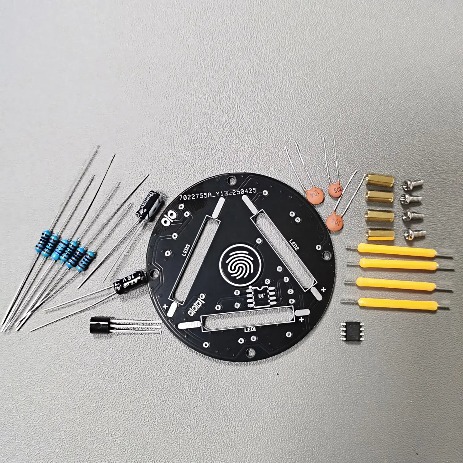 placa de circuito circular negra con diseño de sensor de huellas y componentes etiquetados dispuestos a su alrededor para el uso del kit de soldadura DIY de LED regulables mediante contacto