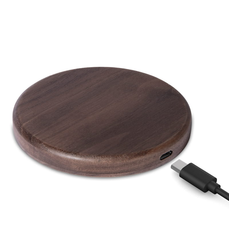 Dark brown walnut wood wireless charging pad with circular shape and USB-C port on the side supporting 15w fast charging.