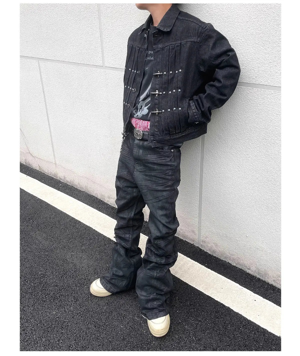 Jeans empilés en denim noir Y2k vintage pour hommes associés à une veste en denim noire présentant des fermetures à pression à tons argentés et des clous décoratifs le long de l’avant.