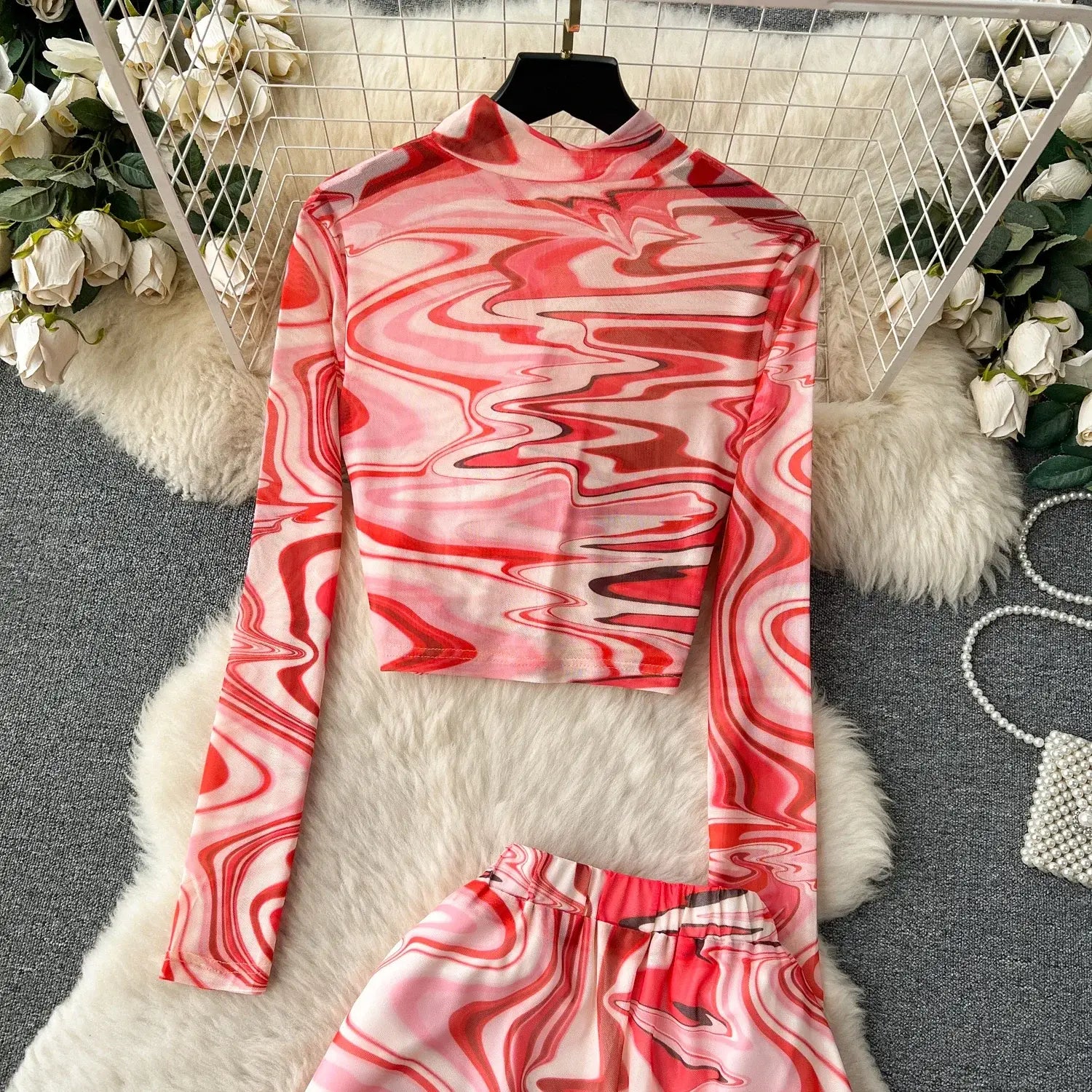 a long-sleeved high-necked top in a two piece mesh skirt set features a vibrant red and pink marble print with an elastic closure type.